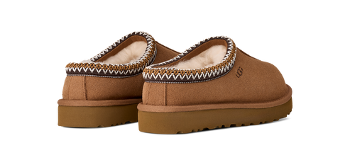 A pair of brown UGG slip-on shoes with white trim and a flat sole.