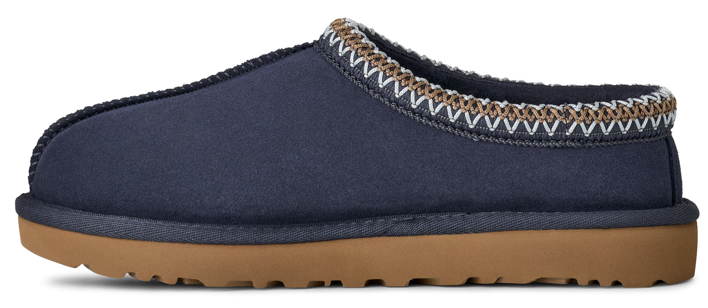 A slip-on style shoe, featuring a blue fabric upper, a brown sole, and a patterned trim around the opening.