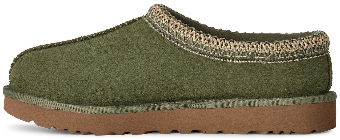 A slip-on olive green suede slipper in profile, featuring a braided, cream-colored decorative trim along the top opening and a thick, flat, tan-colored rubber outsole.
