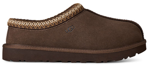 A brown suede slip-on slipper with a decorative woven trim around the collar and an embossed UGG logo on the side.
