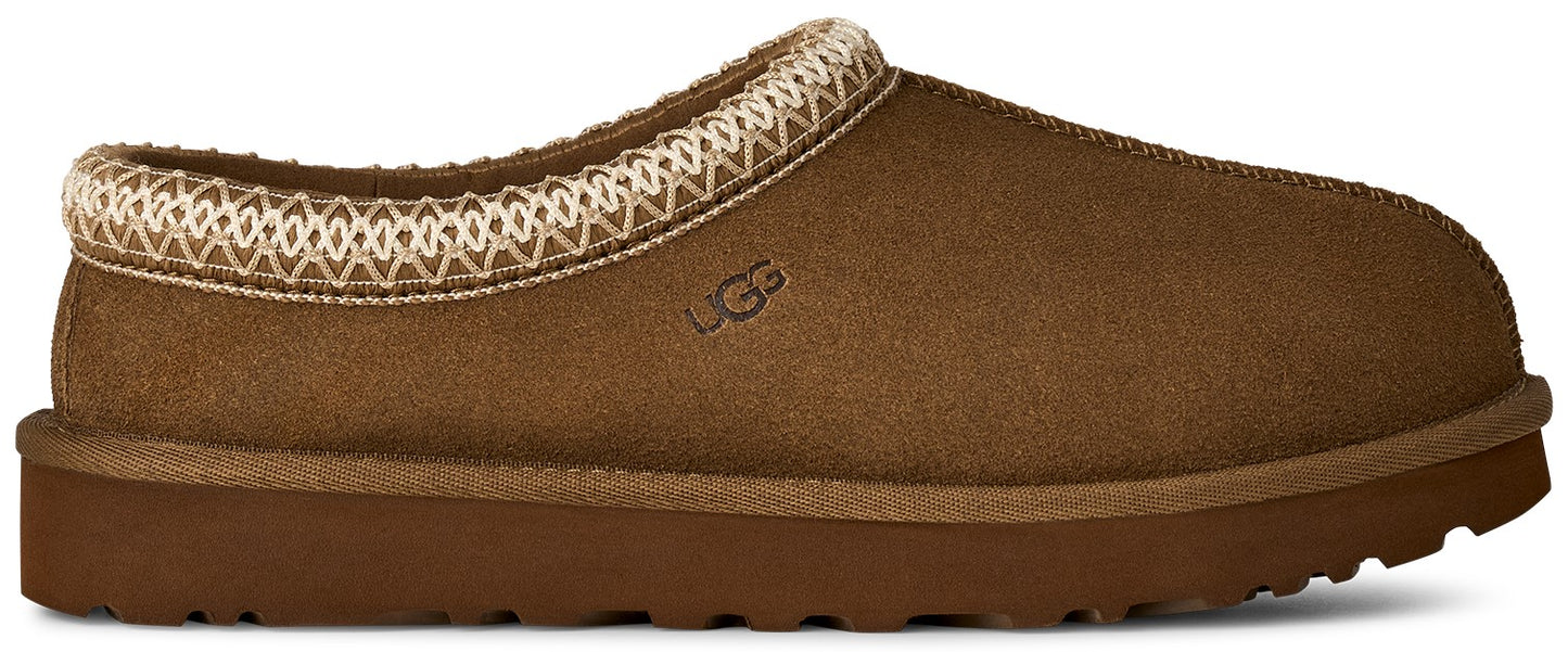A brown suede slip-on slipper with a decorative woven pattern along the collar and the word UGG embossed on the side.