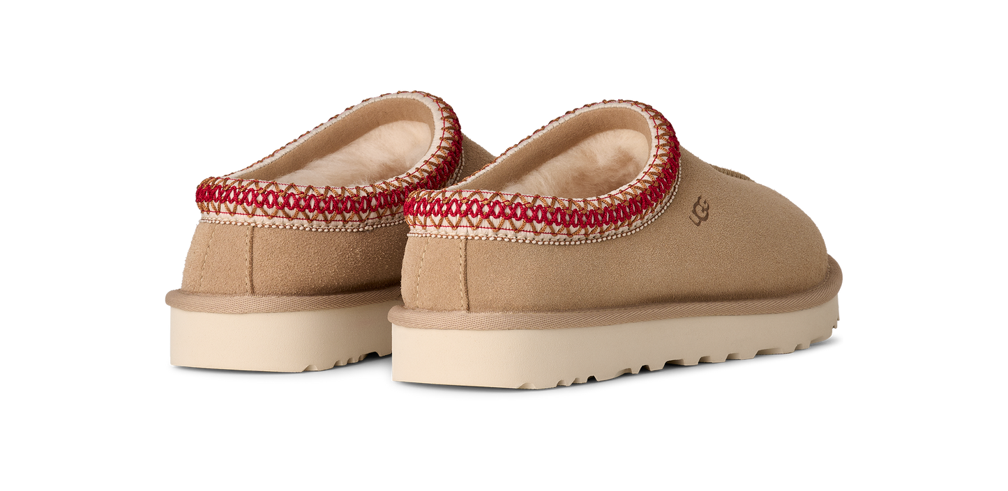 Two low-cut slippers with a tan upper, thick white sole, and decorative red and cream trim around the opening.