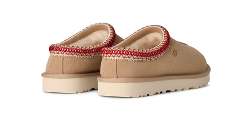 Two low-cut slippers with a tan upper, thick white sole, and decorative red and cream trim around the opening.