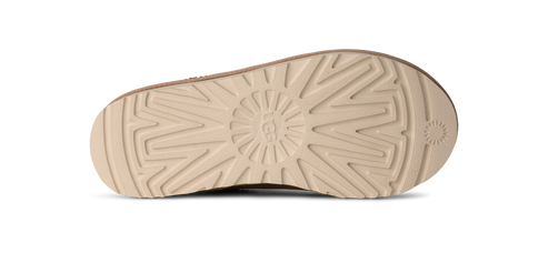 The underside of a shoe displays a grooved, beige-colored sole.