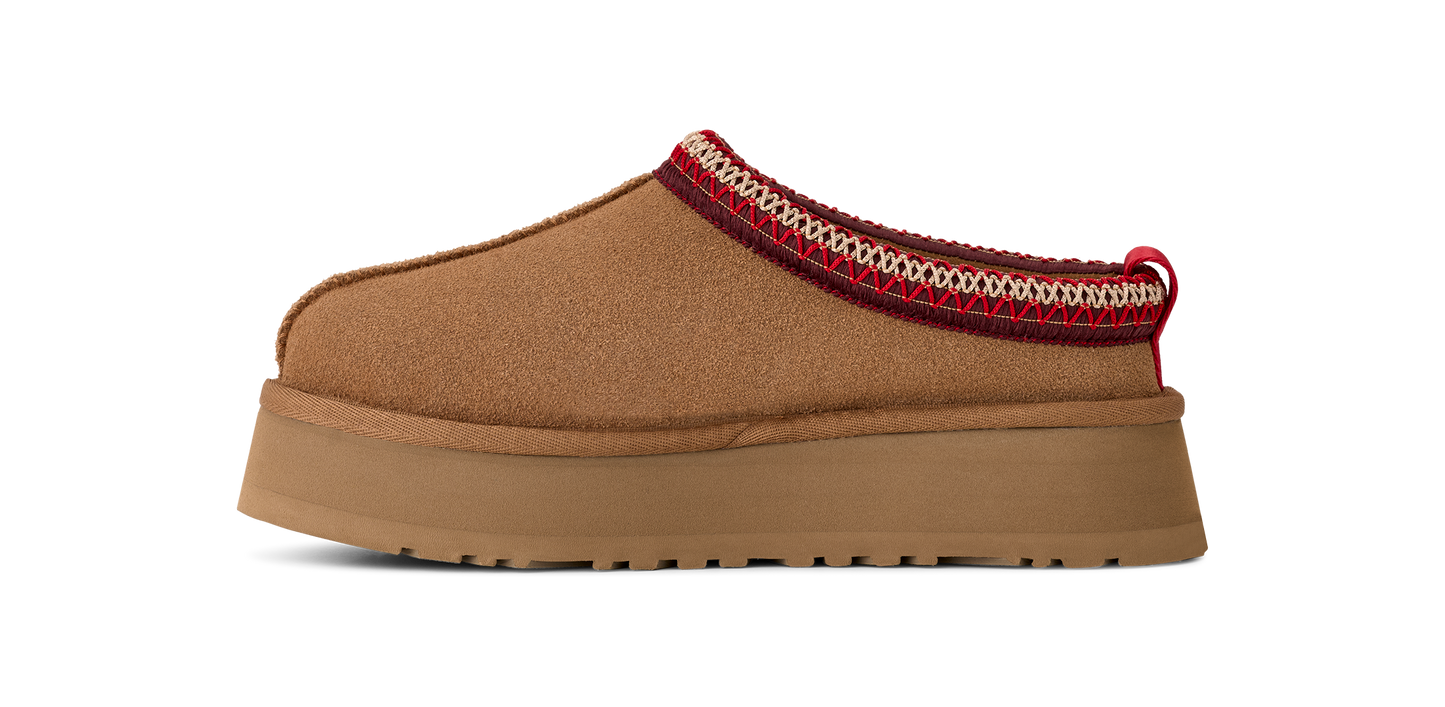 A brown mule shoe with a thick platform sole and a red and white trim.