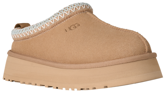 Tan slip-on shoe with a thick platform sole and a white-trimmed opening, with the brand logo visible.