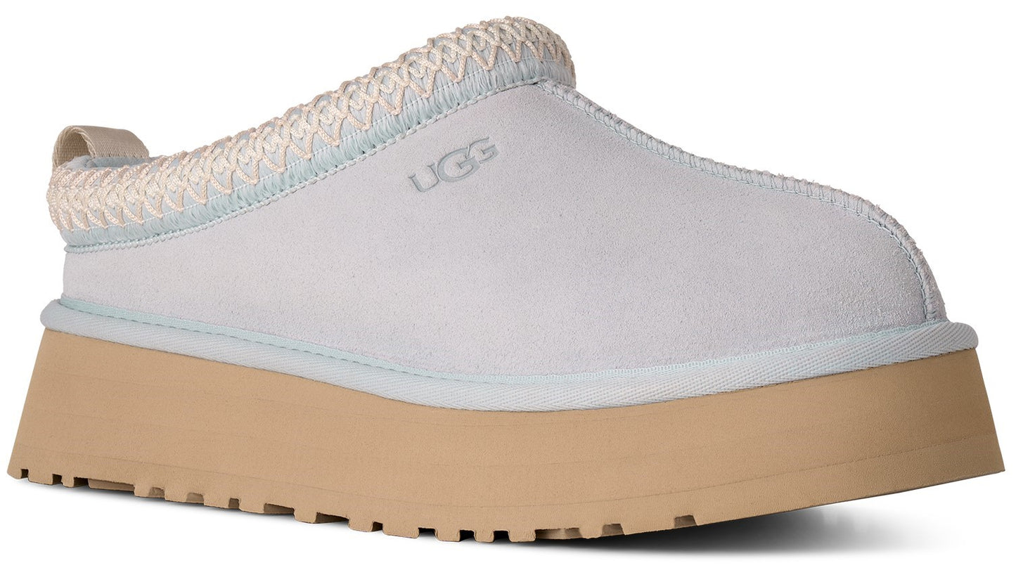 A light blue suede platform mule with a thick, tan, lugged rubber sole and a braided fabric collar featuring the UGG logo embossed on the side.