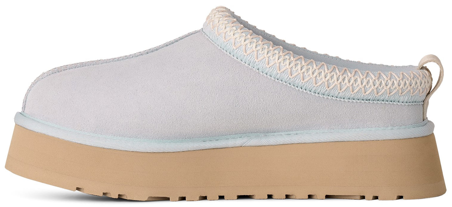 A light grey, suede-like slip-on shoe with a thick, tan, platform rubber sole and a braided trim around the opening.