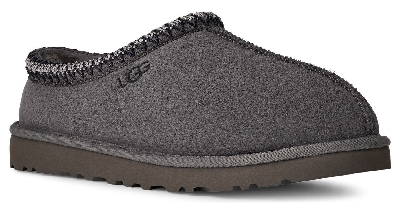Charcoal slipper with woven trim around the opening and a brown sole; the letters UGG are visible on the side.