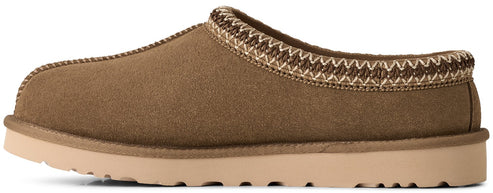 A side view of a tan suede slip-on slipper with a thick, flat light beige rubber sole and a decorative braided trim around the collar.
