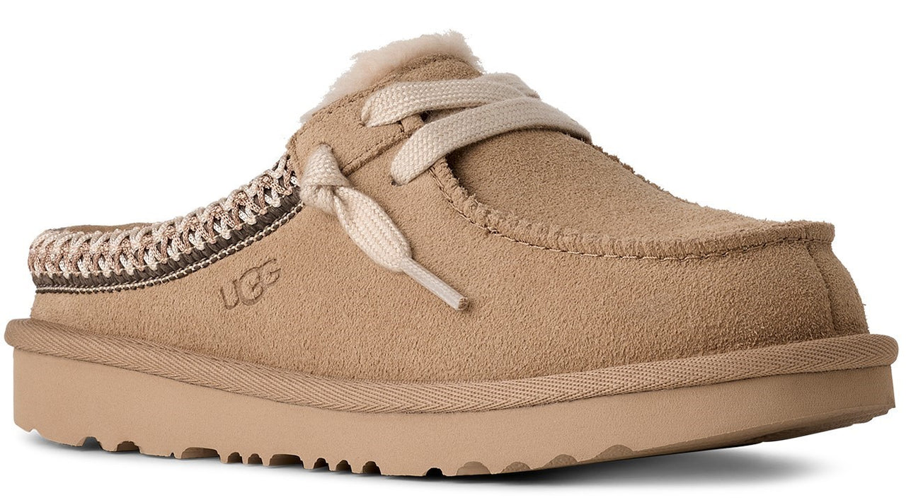 Tan suede clog-style slipper with decorative laces and UGG logo.