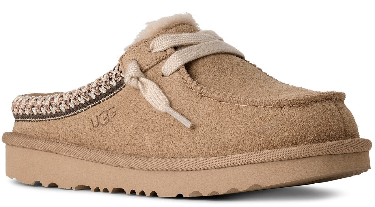 Tan suede clog-style slipper with decorative laces and UGG logo.