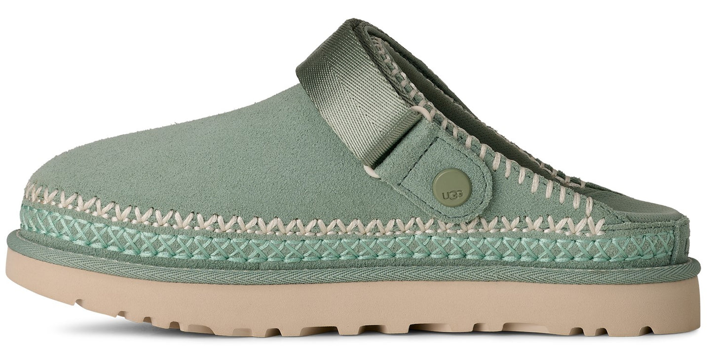 A light green clog-style shoe with a khaki sole, featuring stitching and a strap.