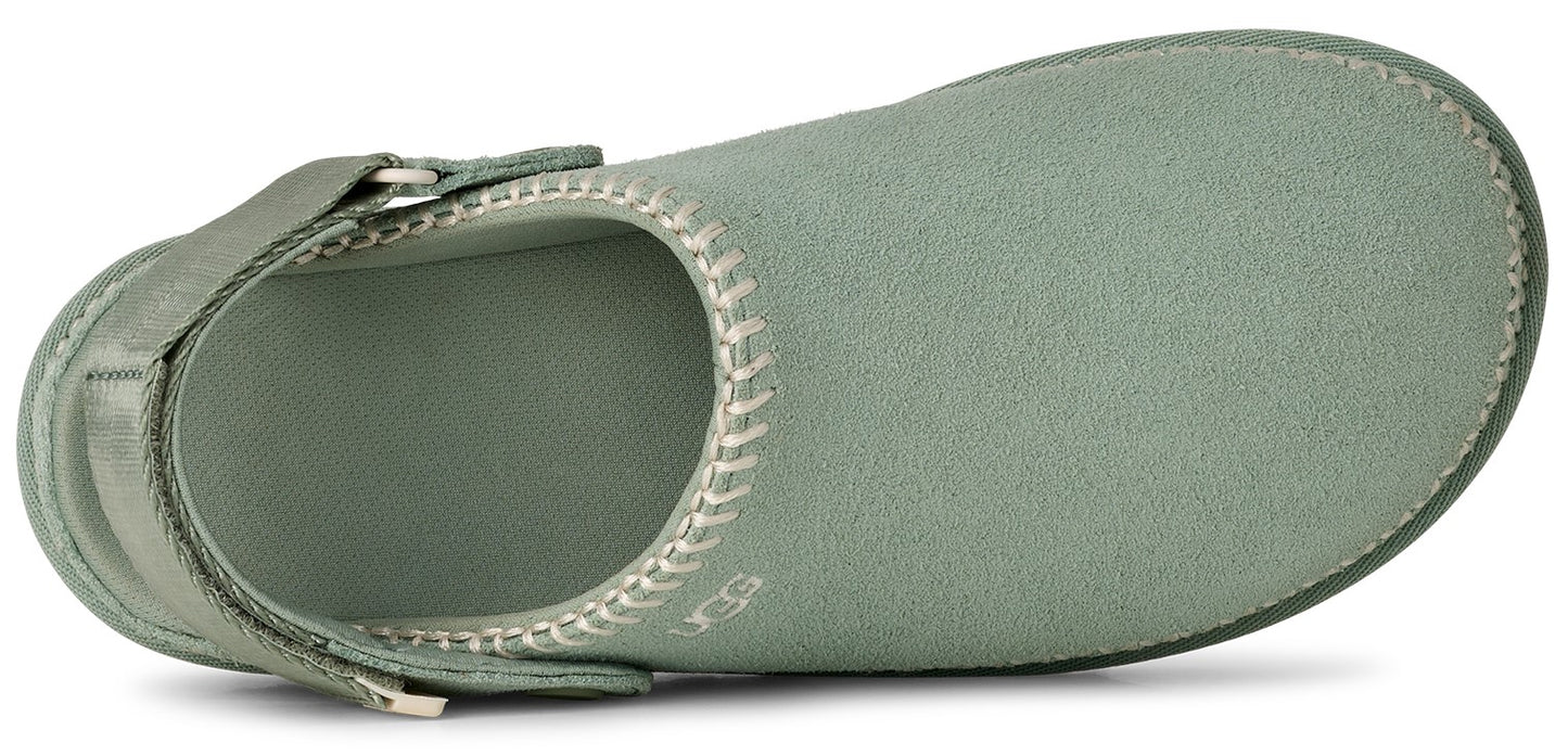 A green, closed-toe slipper with a white stitch detail around the opening.