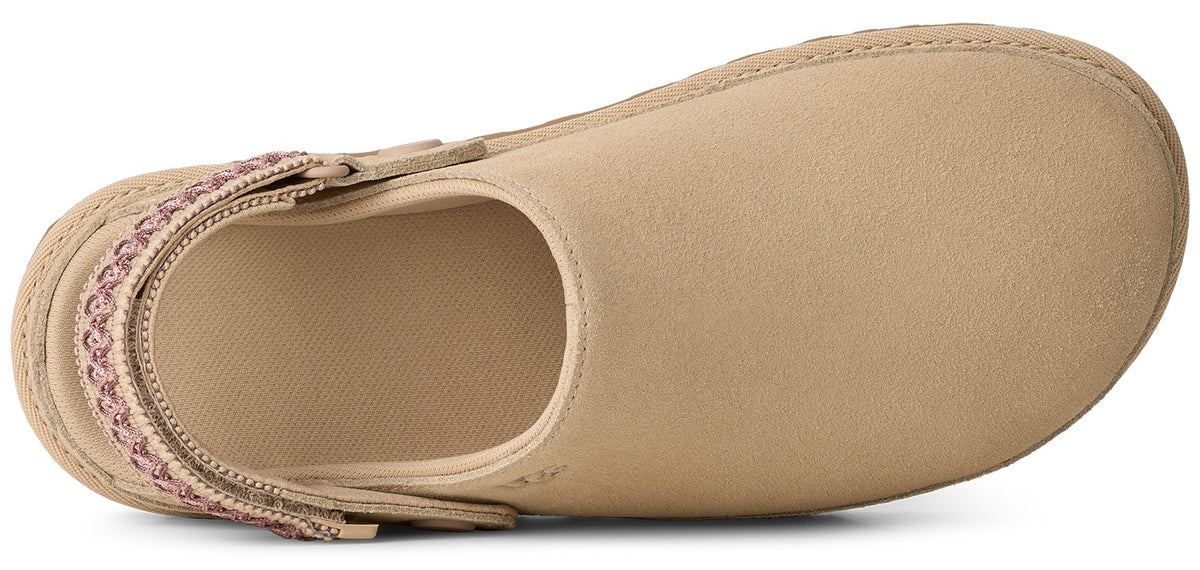 Top-down view of a light beige suede clog-style slipper with a decorative pink and tan patterned fabric heel strap against a plain white background.