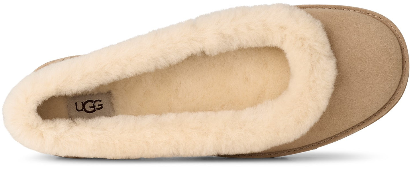 A tan suede slipper with a plush cream-colored shearling lining and a visible UGG logo on the heel.