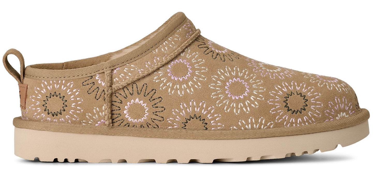 A khaki colored slip-on shoe with flower patterns and a platform sole.