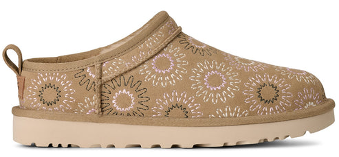 A khaki colored slip-on shoe with flower patterns and a platform sole.