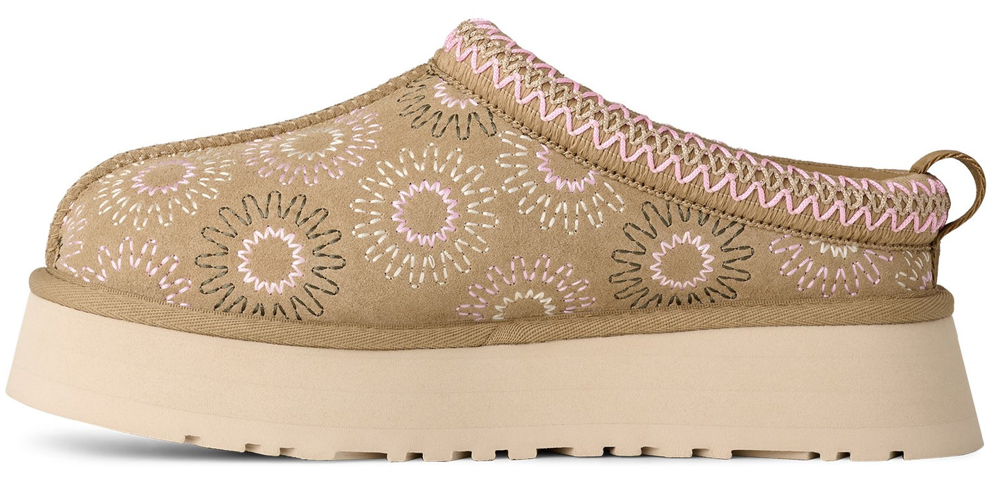 A platform slip-on shoe in a tan color with a floral-like pattern.