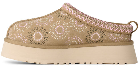 A platform slip-on shoe in a tan color with a floral-like pattern.