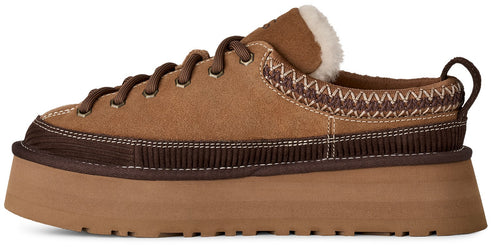 A brown suede platform shoe with a thick, tan rubber sole, dark brown ribbed detailing along the base, a decorative zigzag embroidered pattern around the collar, a fleece-lined interior, and brown laces.