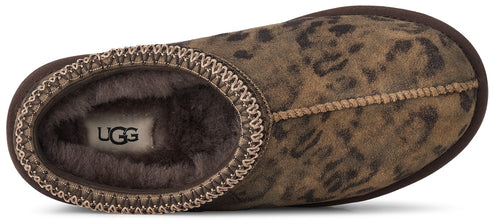 A top-down view of a slipper with a brown, leopard-print suede upper, a tan stitched seam across the top, and an interior lined with dark brown fuzzy fur, featuring the UGG logo on the footbed.
