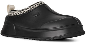 A black slip-on rubber clog with a white woven patterned collar, a beige pull tab on the heel, and a thick, chunky rubber sole, featuring the embossed UGG logo on the side.