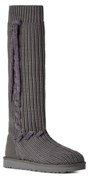 A gray, knee-high, ribbed knit boot with a suede heel counter and a lace-up detail along the side shaft.