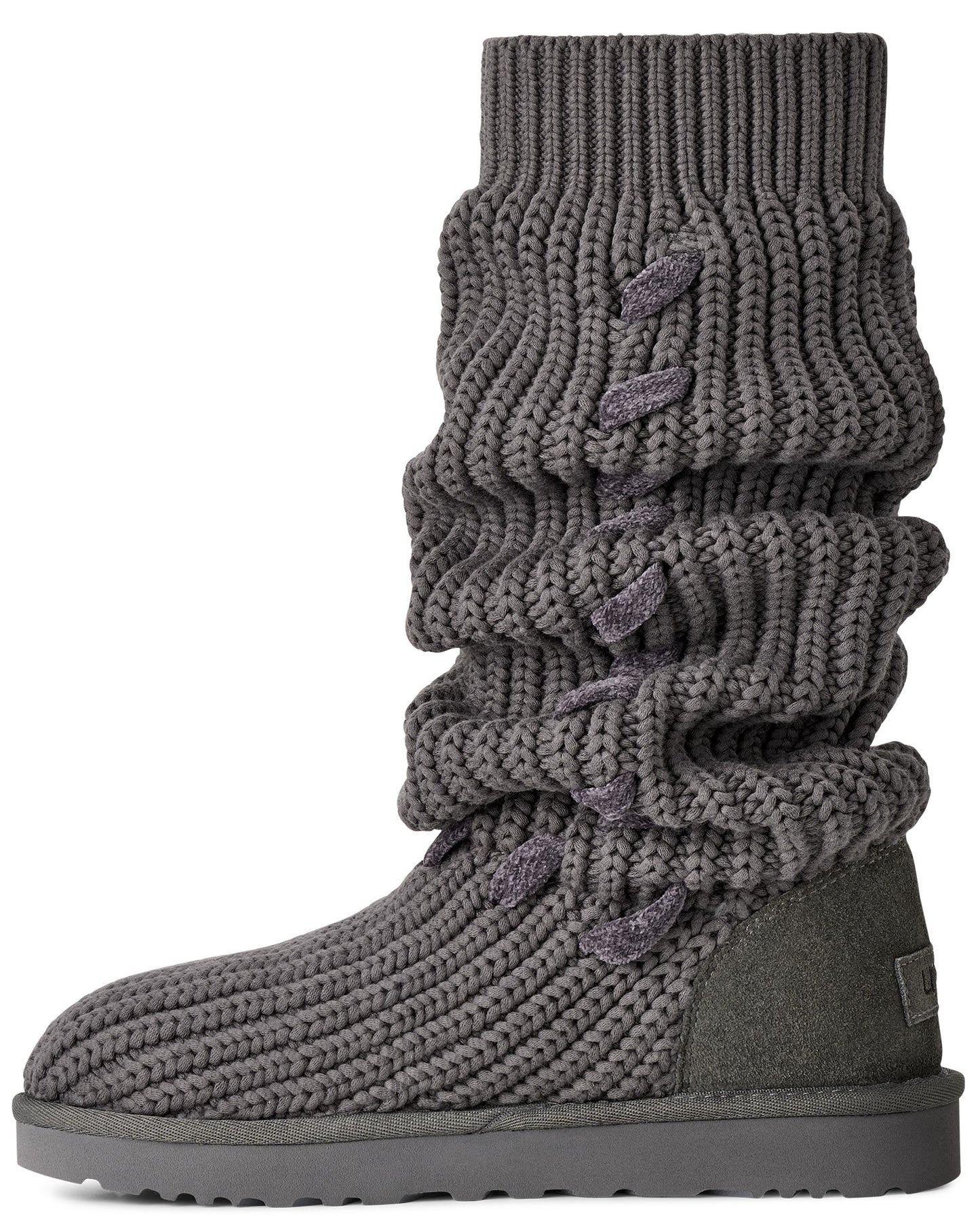 A gray mid-calf slouchy knit boot with a textured ribbed surface, featuring side-lacing details on the shaft and a flat, thick tonal sole.