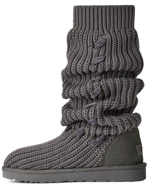 A gray mid-calf slouchy knit boot with a textured ribbed surface, featuring side-lacing details on the shaft and a flat, thick tonal sole.