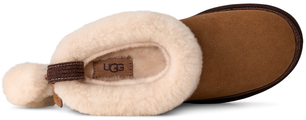 A top-down view of a chestnut-colored suede slipper with a thick cream-colored shearling lining, a brown pull tab at the heel, and a prominent UGG logo on the inner sole.