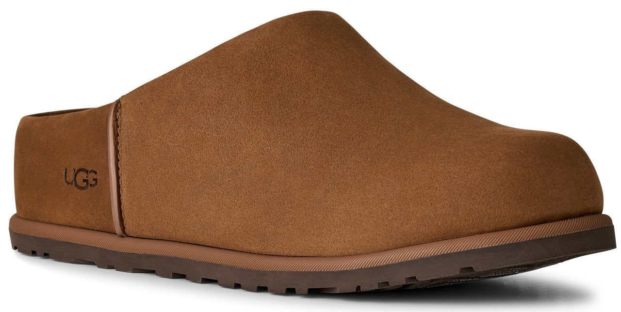A brown suede slip-on mule shoe with a rounded toe, a textured rubber sole, and the logo UGG embossed on the side.