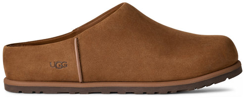 A brown suede slip-on mule shoe with a flat, dark brown rubber sole and the word UGG embossed on the side.