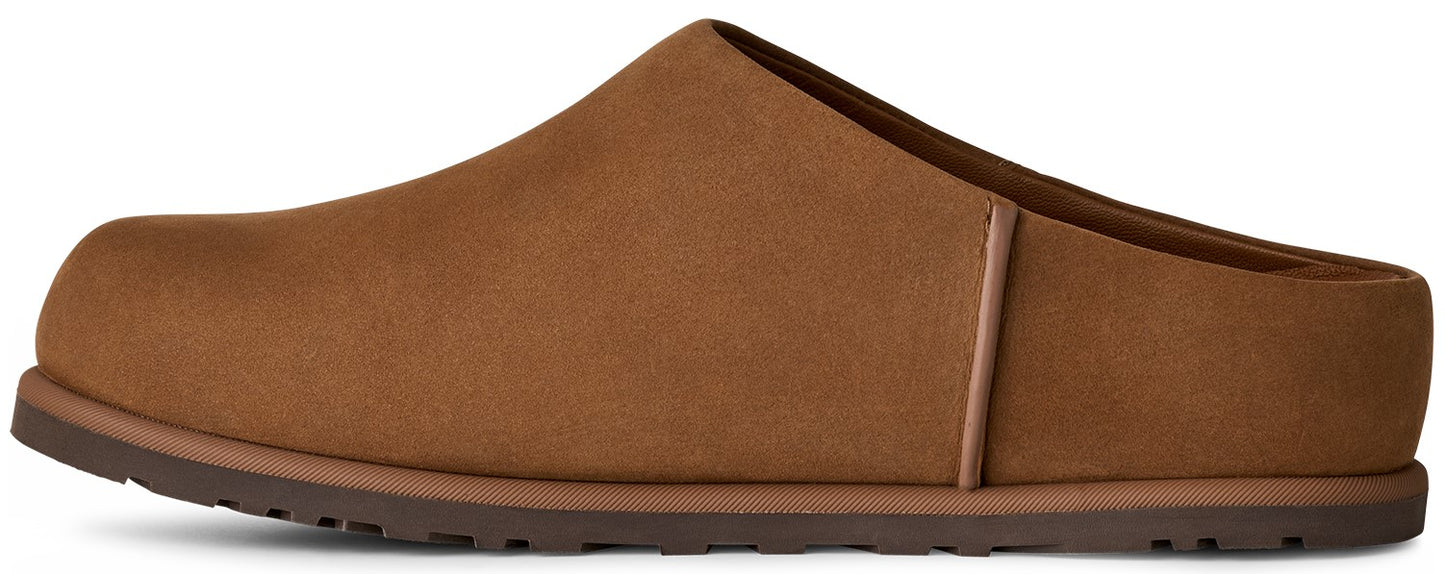 A brown suede slip-on mule shoe with a flat, dark brown rubber sole and a visible seam along the mid-side.