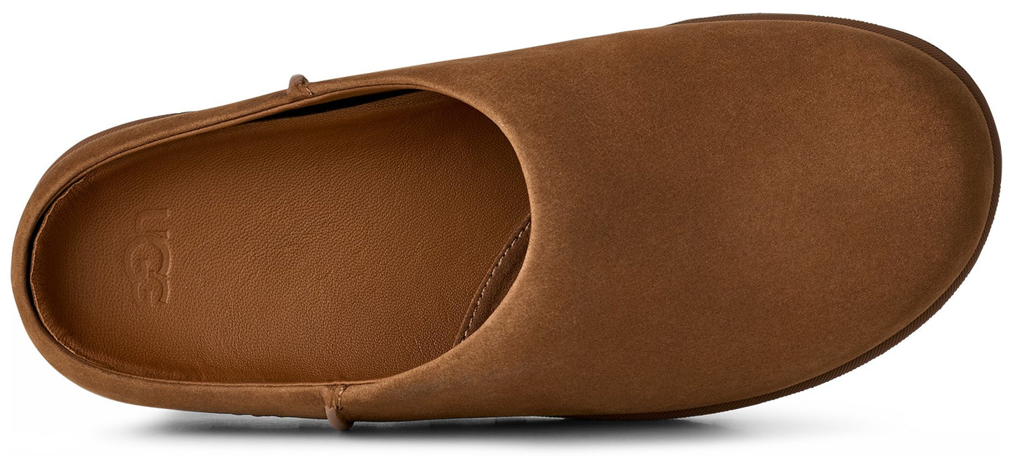A tan suede slip-on shoe seen from a top-down angle, featuring a smooth rounded toe and an UGG logo debossed on the insole.