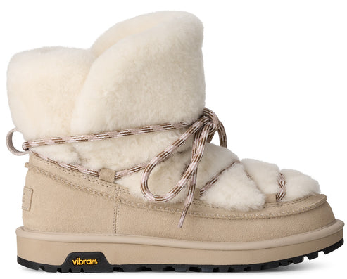 A tan suede lace-up winter boot with a thick cream-colored sheepskin lining, wrapped with patterned laces and featuring a black Vibram rubber sole.