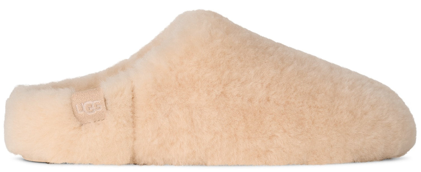 A light beige, fuzzy, slip-on slipper made of soft, textured material, featuring a small logo patch on the side near the heel.