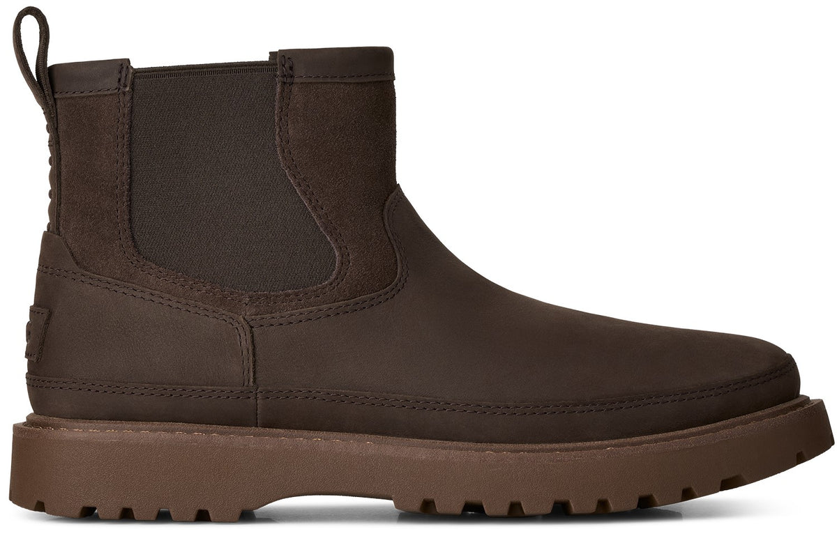 A brown Chelsea boot made of a matte, water-resistant material, featuring a flexible elastic side panel, a pull tab at the heel, and a thick, chunky, lug-style sole in a slightly lighter shade of brown.