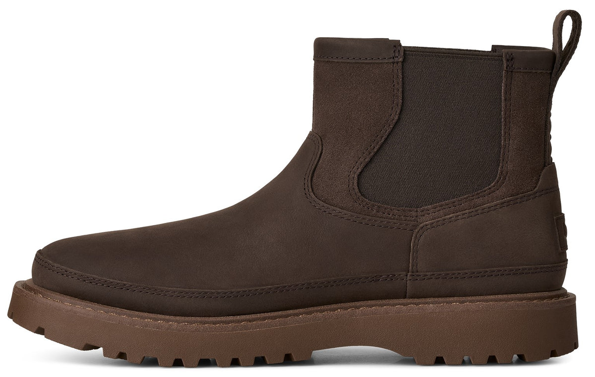 A brown Chelsea boot made of matte leather with a pull tab on the back, elastic side panels, and a thick, textured, lug-soled platform sole.