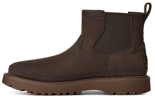 A brown Chelsea boot made of matte leather with a pull tab on the back, elastic side panels, and a thick, textured, lug-soled platform sole.