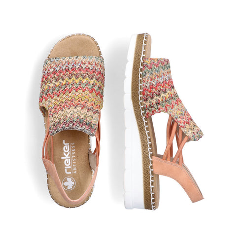Two flat rieker sandals, multi-colored woven straps, peach accents, white soles. The left sandal shows the inside label 'rieker ANTISTRESS'.