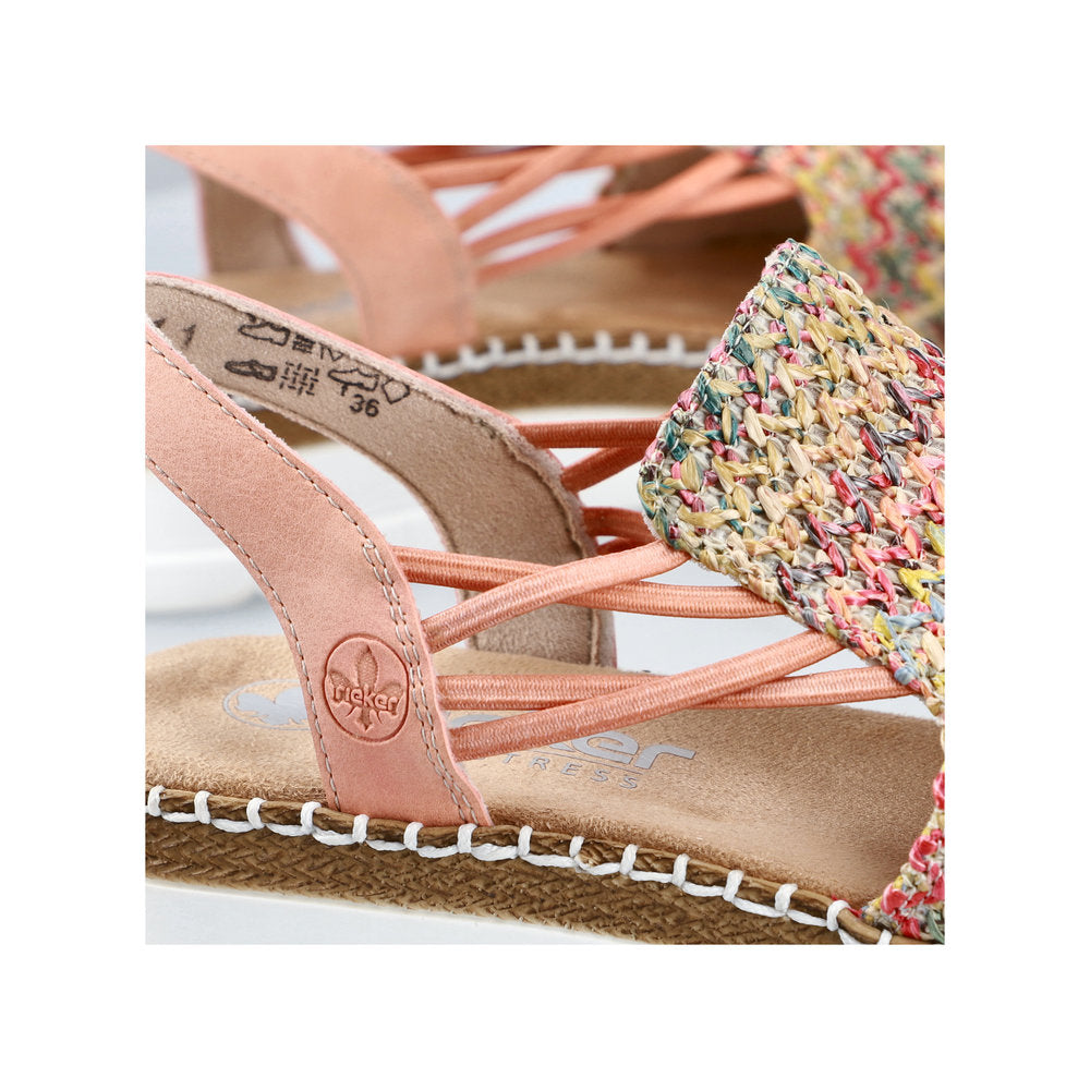 A close-up of peach sandals with interwoven straps and multicolored woven toe boxes.