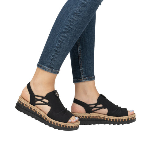 Person wearing open-toe black platform sandals with woven straps.