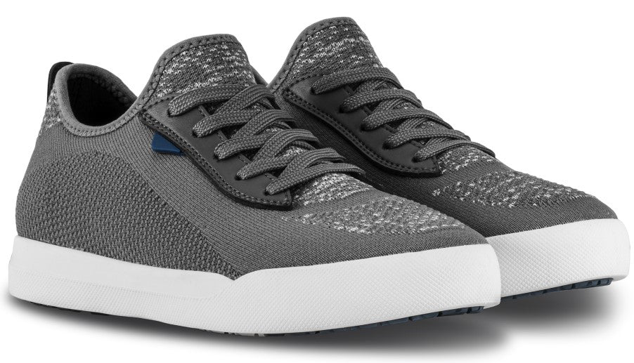 A pair of grey, low-top knit sneakers with white rubber soles and dark grey laces.