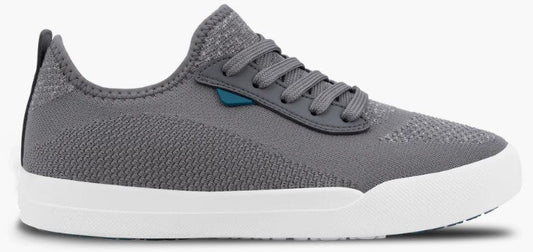A gray knit sneaker with a white rubber sole, laces, and a small teal tab on the side.