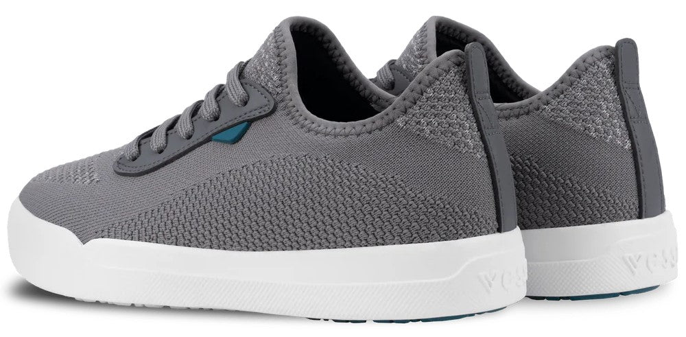 A pair of grey, low-top knit sneakers with white rubber soles and a dark blue accent on the side near the laces, viewed from the side-rear angle.