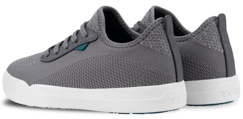 A pair of grey, low-top knit sneakers with white rubber soles and a dark blue accent on the side near the laces, viewed from the side-rear angle.