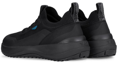 A pair of black Vessi slip-on sneakers seen from a rear three-quarter angle, featuring a textured knit upper, thick matching black soles, and patterned pull tabs on the heels.