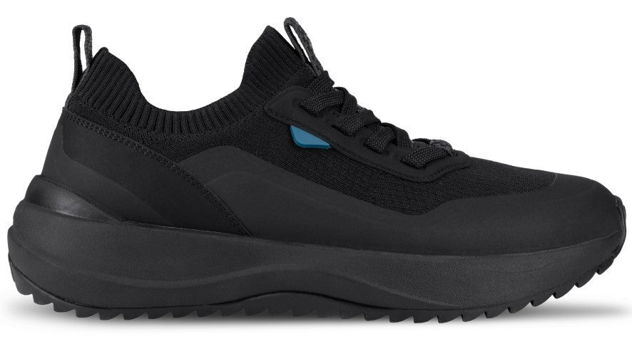 A black slip-on sneaker with a thick, textured black sole, a ribbed fabric collar, and a small blue accent near the lace eyelets.