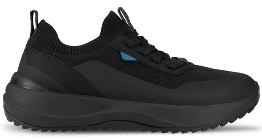 A black slip-on sneaker with a thick, textured black sole, a ribbed fabric collar, and a small blue accent near the lace eyelets.